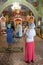 Godmother with kid wearing chrisom stand in the Orthodox church. Mother standing close to the baptistery. Ceremony of sacrament of