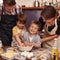 This is going to be delicious. Two cute little boys baking with their parents in the kitchen.