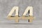Gold 3d number 44. Glossy golden number on concrete background. 3d rendered digit