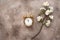 Gold alarm clock and blossoming cherry branch artificial on a beige grunge background. Spring time. Creative layout. Top view,