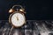 Gold alarm clock on a vintage wooden dark table. Rustic style. Selective focus, copy space. Time five minutes to twelve