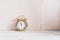 Gold alarm clock on a wooden vintage white table, shabby backdrop. Minimalistic home decor. Modern stylish composition