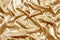 Gold beautiful satin fabric draped with soft folds, silk cloth background, close-up, copy space