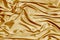 Gold beautiful satin fabric draped with soft folds, silk cloth background, close-up, copy space