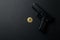 A gold bitcoin coin next to a gun on a black background. Bitcoin Conservation. Cryptocurrency. Close-up