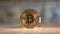 Gold Bitcoin rotate on the table with many other cryptocoins. Golden reflection on it. 100 USD banknote on the