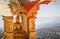 Gold buddha statue in golden recess with buddhist white and orange flags and mountain background