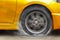 Gold car racing spinning wheel burns rubber on floor.