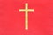 Gold catholic cross on red cloth texture background