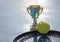 Gold champion trophy, tennis ball and racket on blue background in backlight. Award for the winner. copy space