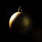 Gold Christmas bauble over dark background. Low key photo. Ball shape.