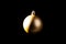 Gold Christmas bauble over dark background. Low key photo. Ball shape.