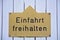 A gold colored sign on a white wall, with the words `Einfahrt freihalten`, translation: keep gateway clear