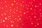 Gold confetti on red paper background. Festive holiday backdrop. Birthday congratulations Christmas New Year. Valentines Day.