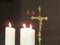 A gold crucifix stands beside lit white candles in a church