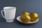 Gold eggs on white saucer with gold border. White small mug. Dark blue background.