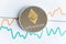 Gold ethereum cryptocurrency coin on spiking line graph trading