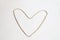 A gold heart is made of chain, symbol of love on a white textural background