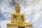 Gold image of Buddha with blue sky and cloud, mountain with temple on hilltop, light effect added in back of image of buddha