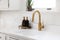 A gold kitchen faucet detail in a white kitchen.