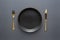 Gold knives and forks on a black background, empty black plate. Beautiful gold cutlery