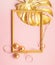 Gold leaf frame of tropical plant Christmas balls serpentine painted in gold color pink background. Festive minimalism.