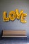 Gold love balloons painted on a brick wall over a bench