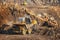 Gold ore mining, loading excavator bucket into body of mine truck