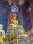 Gold pained Buddha statues in the temple with mural painting.
