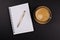 Gold Pen, Notebook, Cup of coffee on a Wooden tray, on black table, shot from above