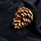 Gold pinecone isolated on black silk. luxury background.