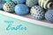 Gold polka dots, glitter and stripes on blue and teal decorated Easter eggs on solid pastel color background