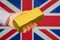 gold reserve of the Great Britain concept. Gold bar in hand on Great Britain flag background