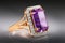 Gold ring with a large amethyst and cubic zirconias on a gradient background