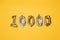 Gold and silvr 10,000 number balloons on a yellow background. Followers and Subscription Concept