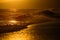 Gold sky and ocean water. Waves splashes. Sunset over sea with golden dramatic sky panorama. Calm sea with sunset sky