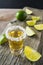 Gold tequila shot with lime slices on rustic wooden table