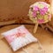 Gold wedding rings and a bouquet of the bride. Pink and white roses. Satin decorative cushion for the rings