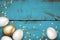 Gold white easter eggs on painted wooden blue background. Easter eggs golden serpentine confetti. Rustic grunge background