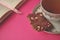 Gold and white porcelain tea cup and saucer with artisan chocolate on bright fuchsia pink background with copy space