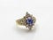 Gold womens ring with diamonds and a blue gem in the form of a flower front view on a white background