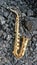 A golden alto saxophone on a background of black coals and burned ebony. Original design or cover for music in the style