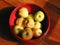 Golden apples in red ceramic bowl, top view