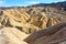 Golden badlands eroded into waves, pleats and gullies at Zabriskie Point in the Death Valley National Park.