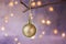 Golden ball Christmas ornament hanging on dry tree branch. Shining garland golden lights. Beautiful pastel background