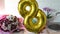 Golden ballon 8 eight and spring flowers on kitchen table with gift box and breakfast. Mothers Day. March 8, International Women`s