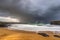 golden beach with view of crashing waves and stormy skies