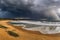 golden beach with view of crashing waves and stormy skies
