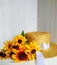 Golden bicolor rudbeckia lies on a wicker straw hat on a light wood background