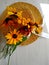 Golden bicolor rudbeckia lies on a wicker straw hat on a light wood background